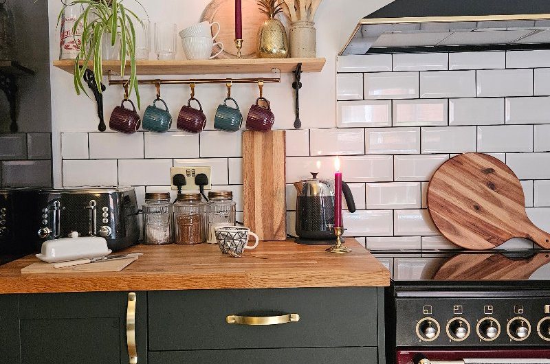 A green kitchen with burgundy range cooker, metro tiles, and wood worktop.
