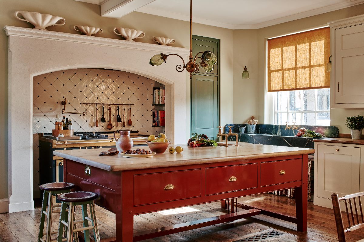 Artisan kitchen design with a freestanding red island, classic cabinetry and glossy tiles.