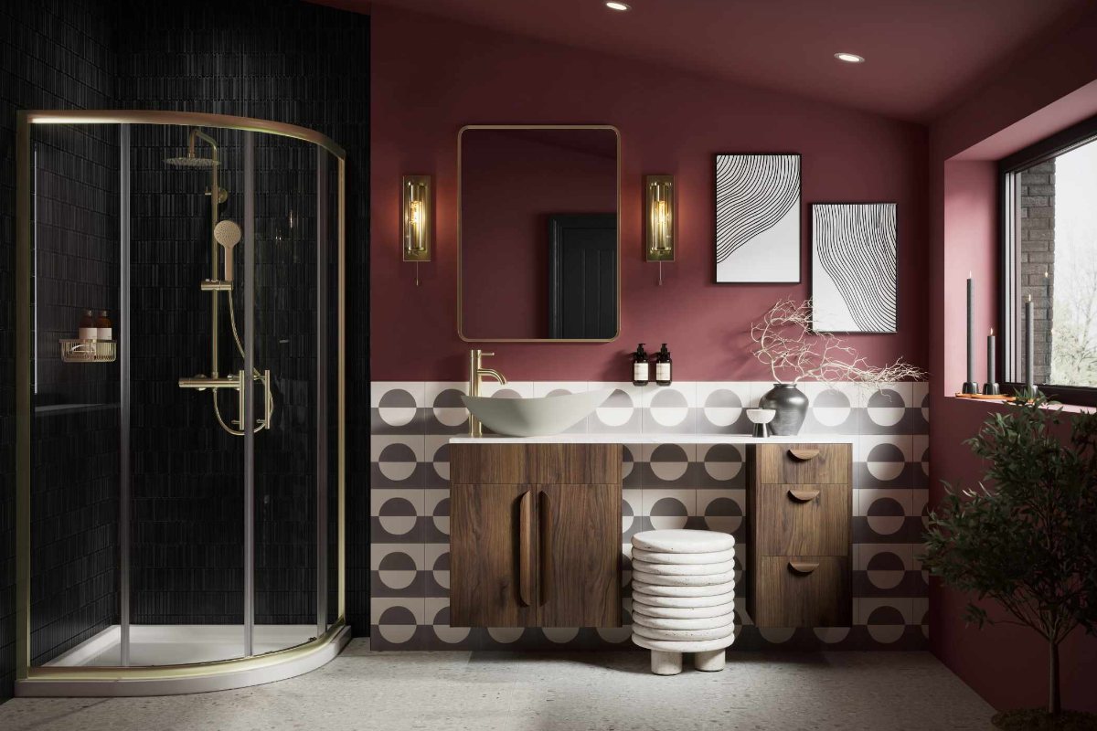 Bathroom design with burgundy wall paint, wall art, geometric tiles, wood furniture, and a shower area with a gold enclosure and matching brassware.