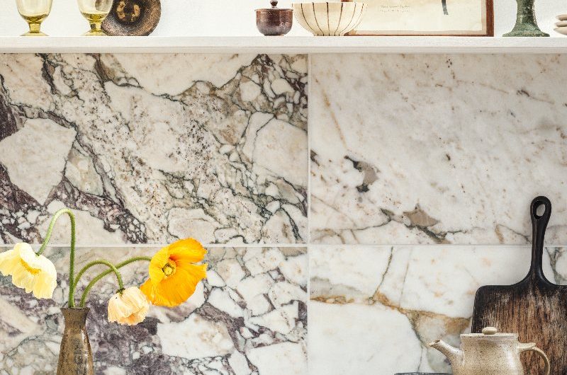 Kitchen design with marble splashback, open shelving, and dark cabinetry.