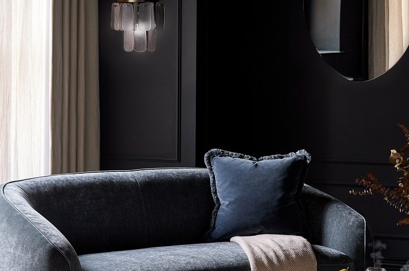 Moody living room drenched in navy with a matching lounge chair, velvet cushion, and marble coffee table.
