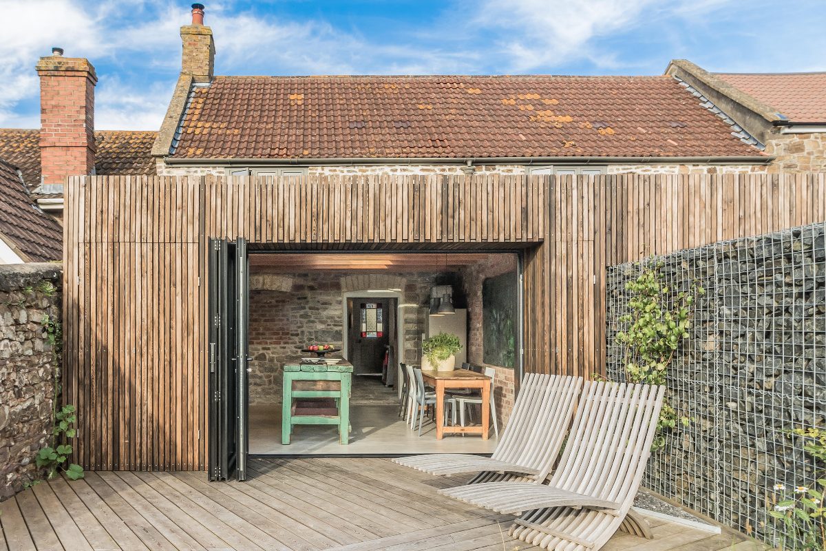 A wooden building with chairs and a table mirroring the interiors.
