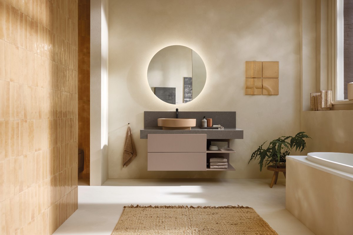 Neutral bathroom with wall-mounted vanity, circular mirror and fitted tub.