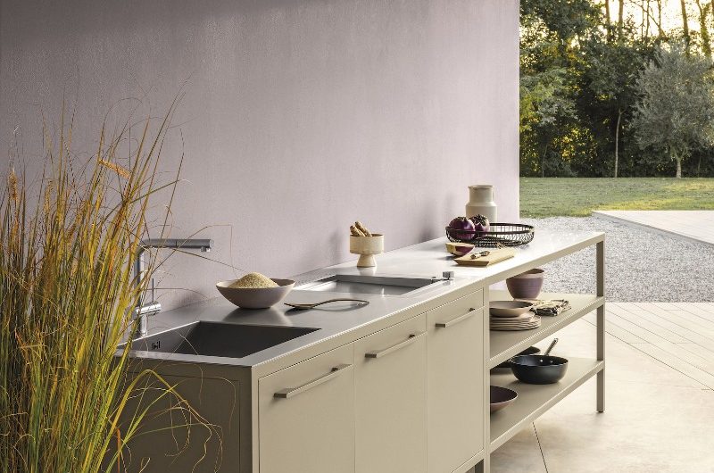 Neutral, modern outdoor kitchen with a workstation, staineless steel worktop, and a sink and tap zone.