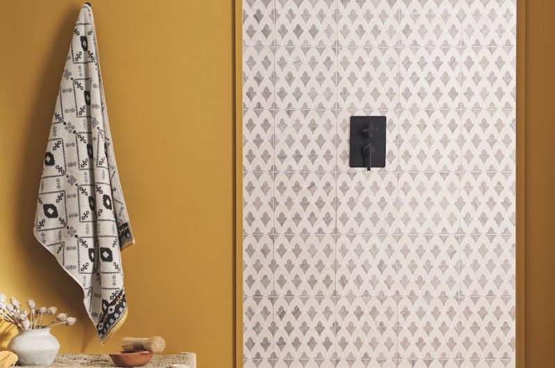 An arched shower zone with patterned tiles on the wall, black shower system, and spa-like decor.