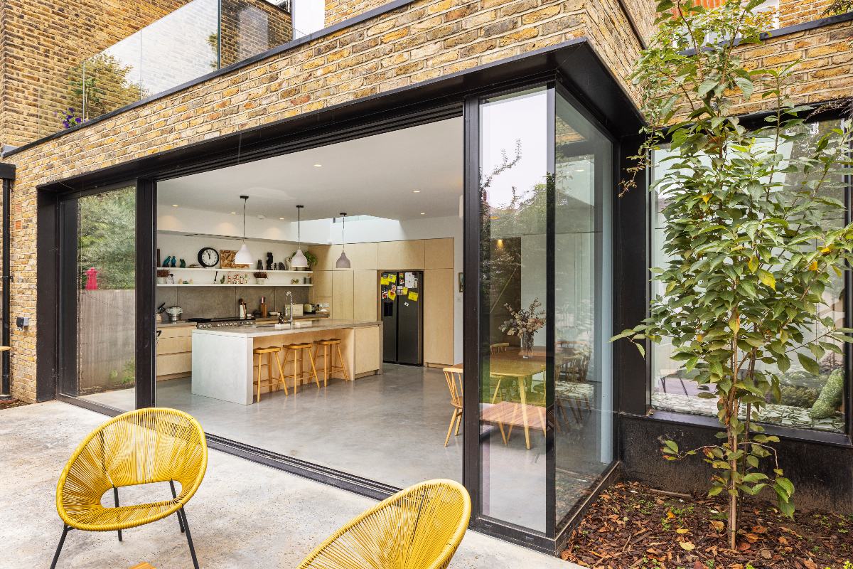 Open glass sliding door to a wood kitchen-diner.