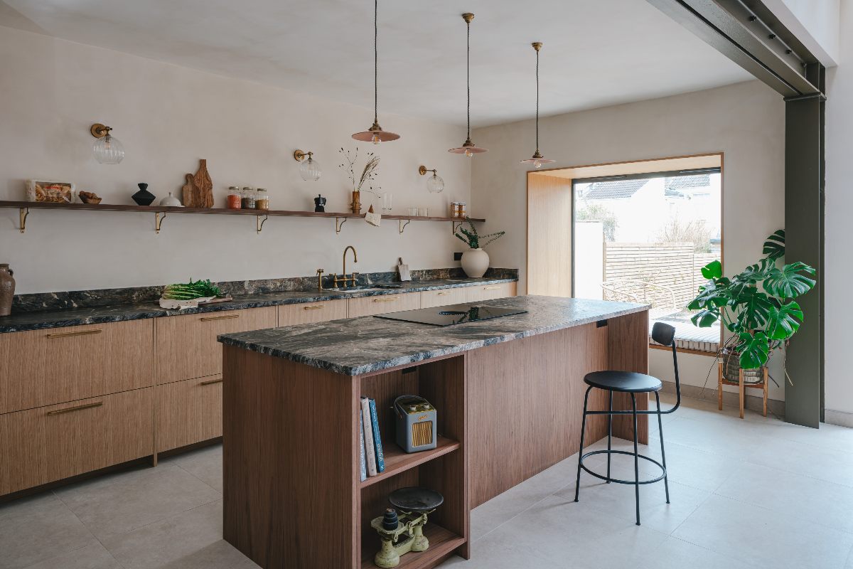 A wood kitchen design with marbled surfaces, a window nook, and open shelving.