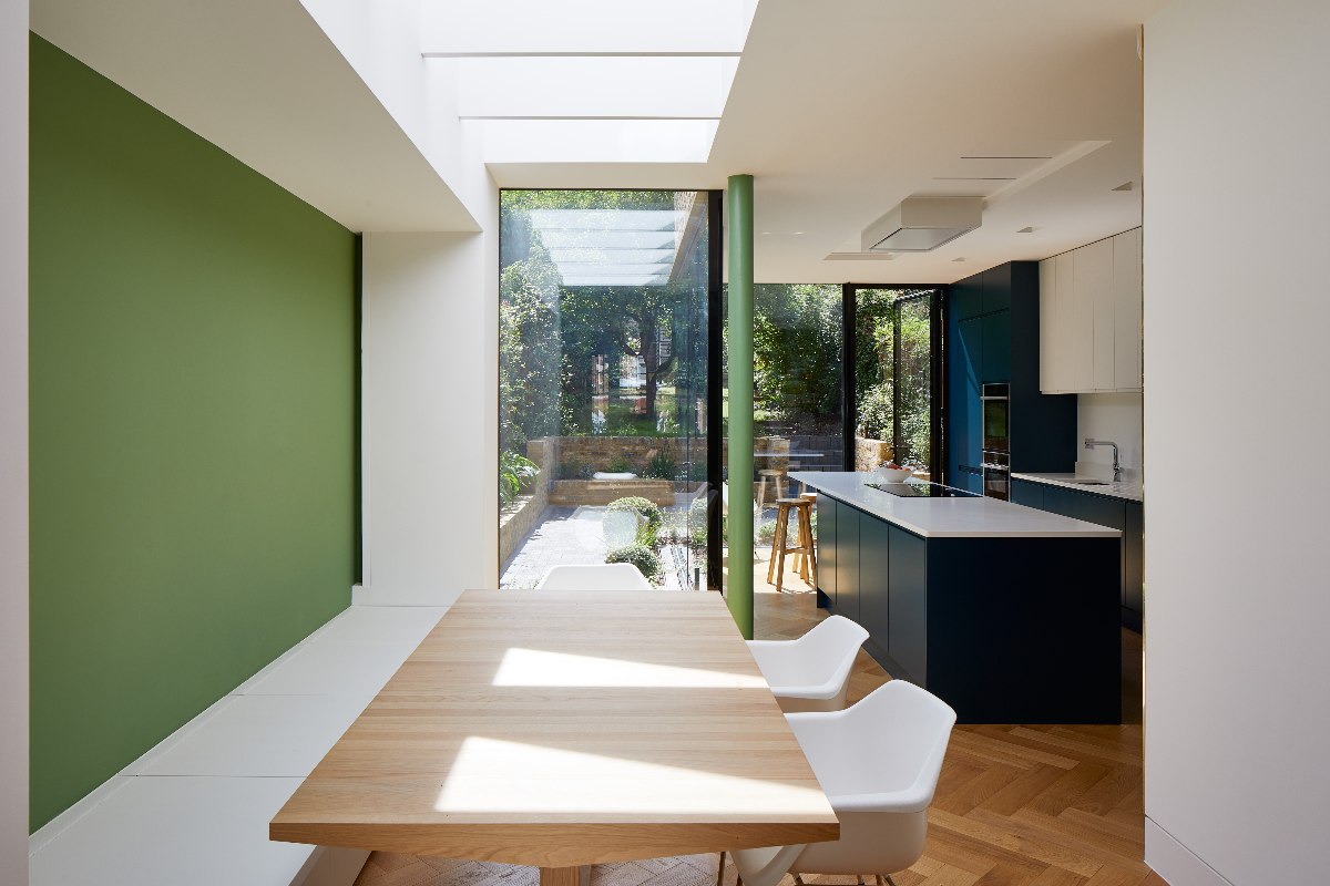 An open-plan extension with a table and chairs, and cabinetry near the garden area.
