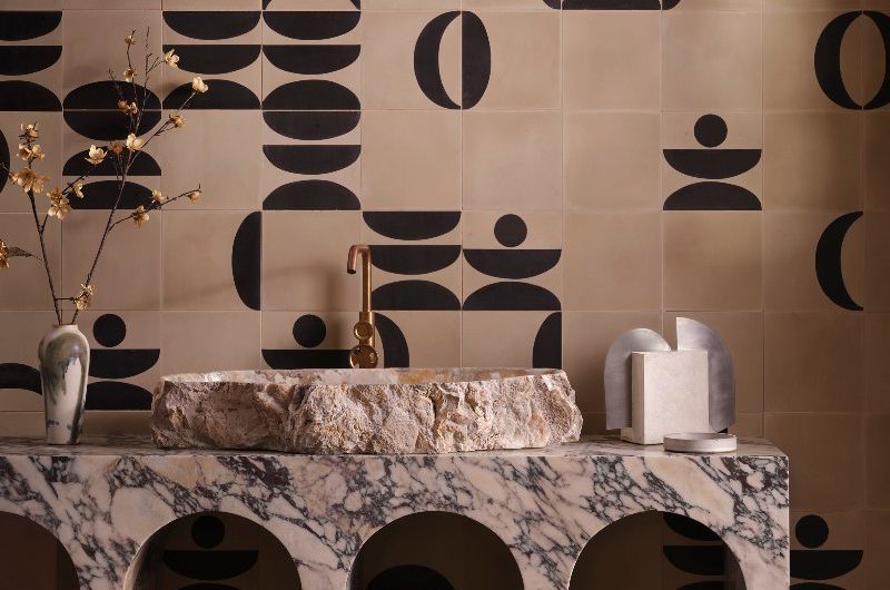 Bathroom vanity zone with a marble stand, stone basin, small tap, and geometric wall coverings.