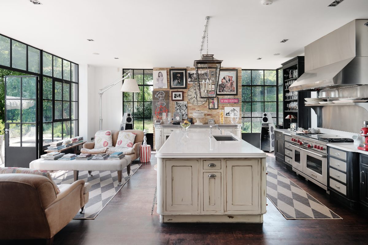 Galley kitchen with a cream island, with an adjoining living area by the Crittall windows.