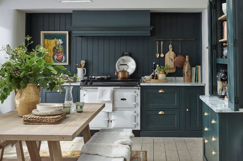 Green kitchen design with a farmhouse-style dining table with matching wood benches.