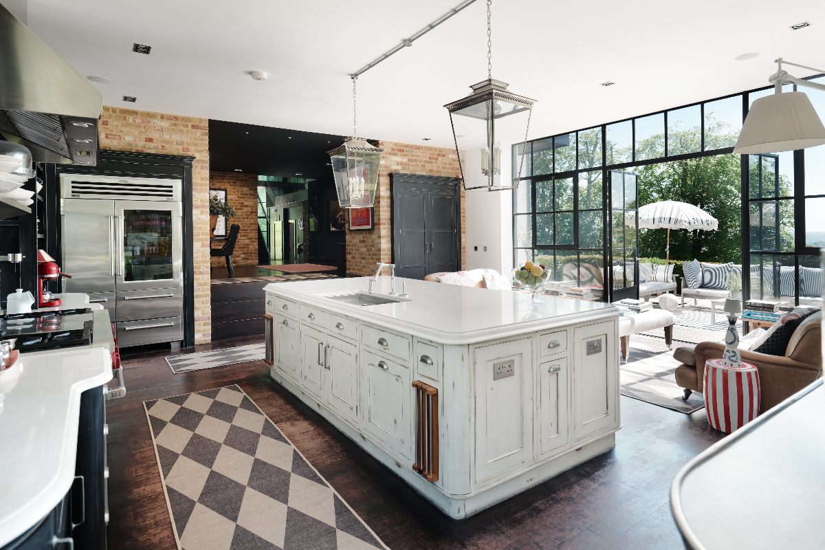 An industrial kitchen with a central island enjoys views of the garden through Crittall glazing.