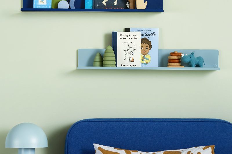 Kids bedroom with a blue single bed, blue open shelves and green locker style nightstand.