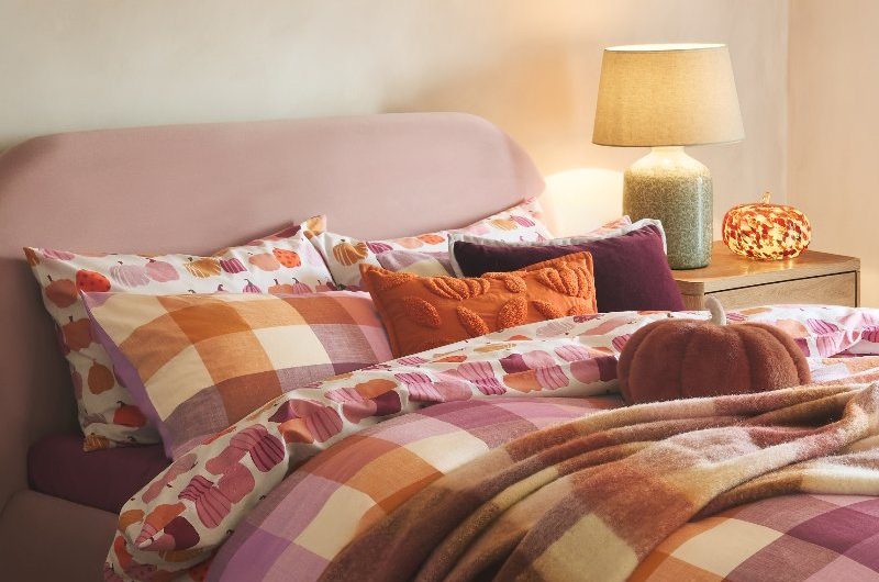 Bedroom design with checkered bedding, mood lighting, and pumpkin shaped cushion.