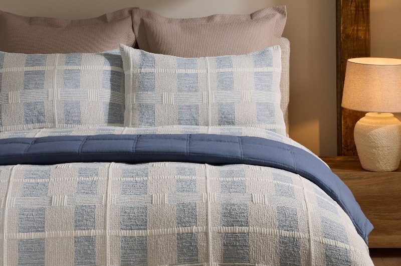 A calming autumn bedroom with pale blue bedding, wood furniture, and mood lighting.