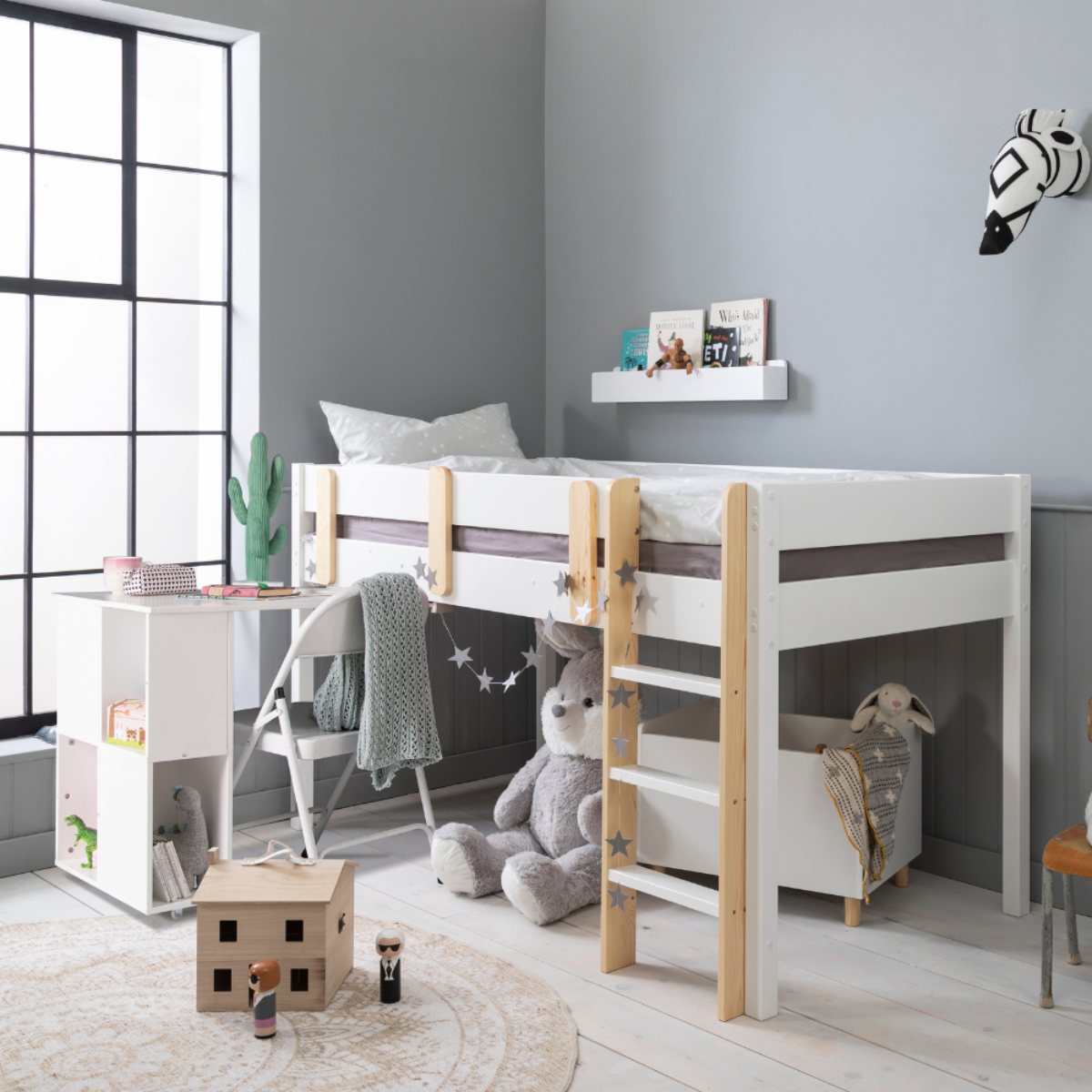 An elevated bed with built-in desk and chest of drawers, and space for storage underneath.