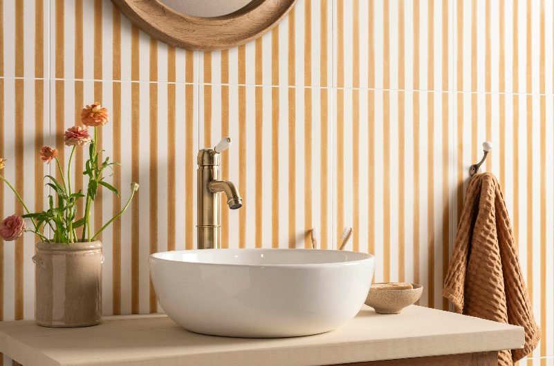 Vanity zone with a vintage unit, countertop basin and striped tiles on the wall behind it.