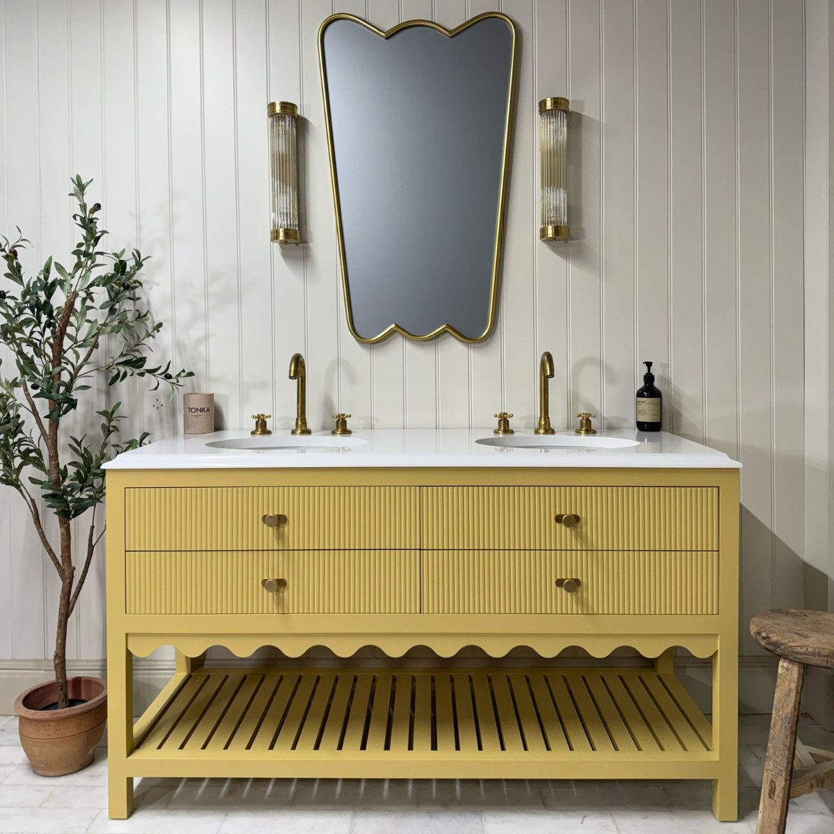 A neutral scheme with a reeded and scalloped vanity with double basins and matching brassware.