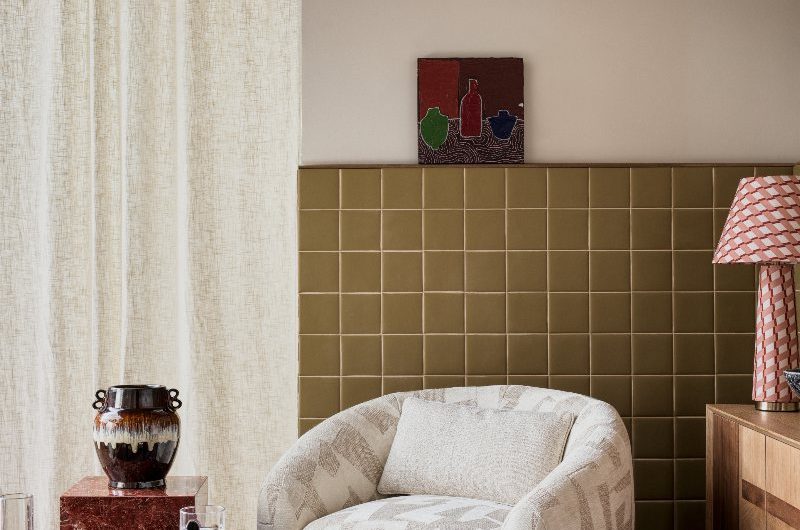 Retro living room with green tiles, navy carpet, geometric furnishings and wood furniture.