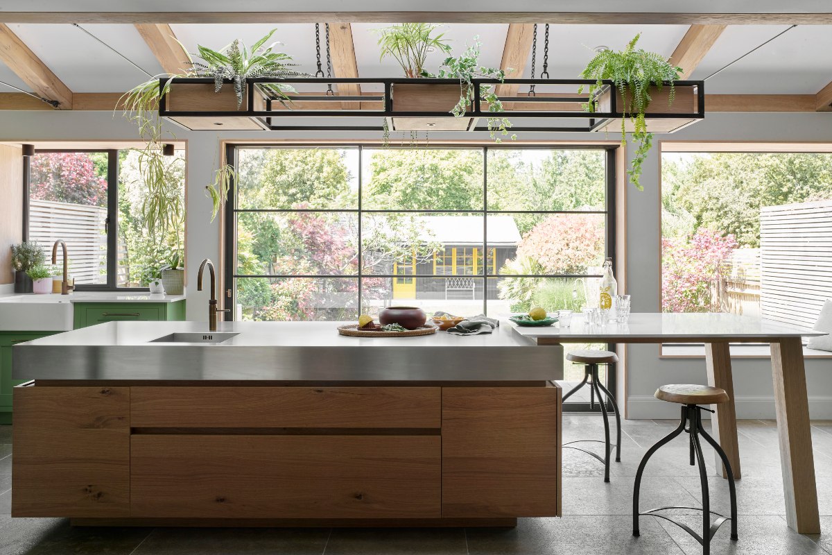 A kitchen with a large rough sawn oak island and plants for an indoor-outdoor connection.