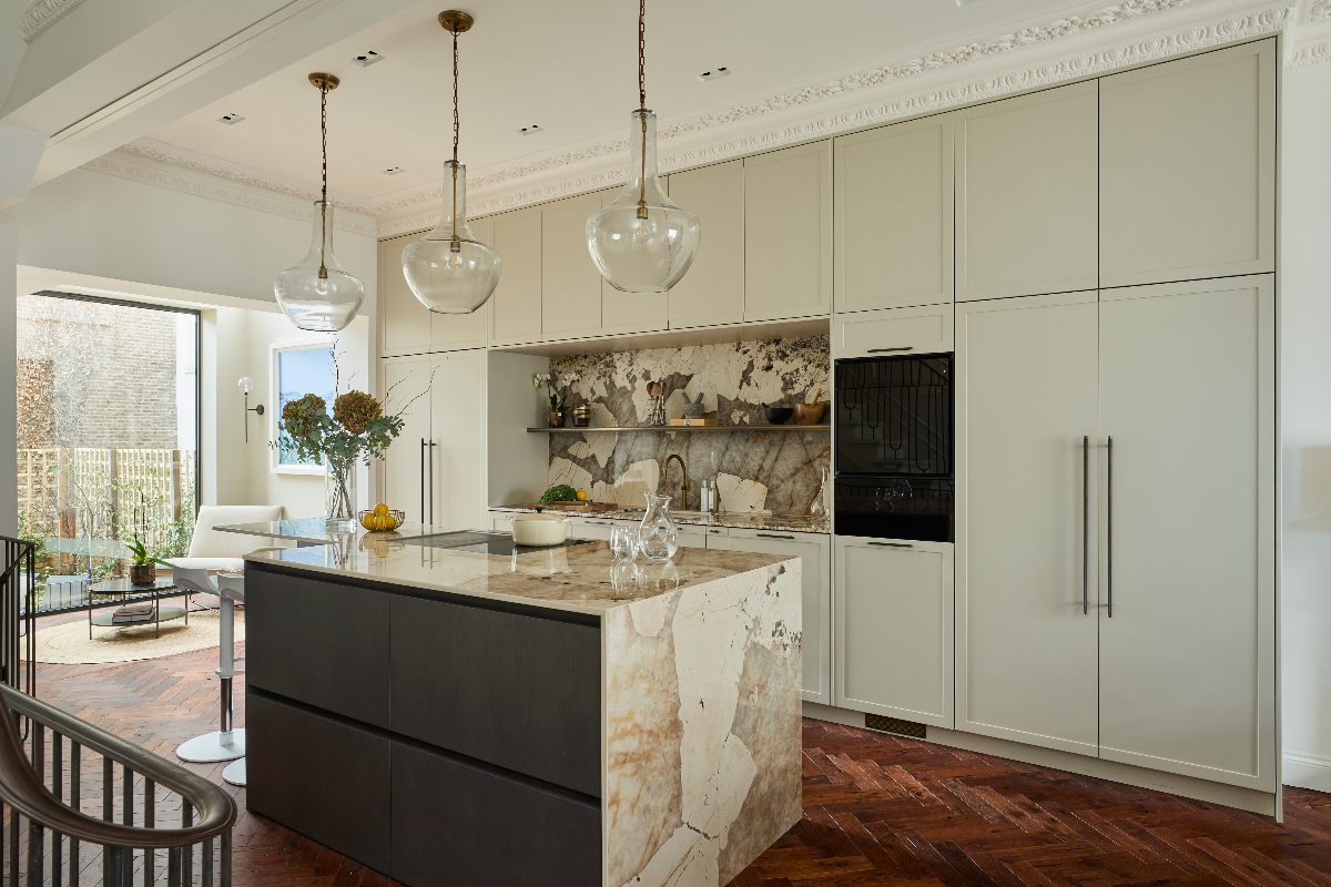 Galley kitchen with slim frame cabinets, an island, herringbone flooring, statement lighting and marbled stone surfaces.