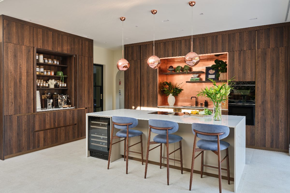A wood kitchen with an island with bar stools and hob.
