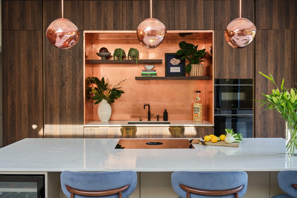 Zoe Hardman's kitchen with floor-to-ceiling cabinetry, a veiny stone-clad island, and copper fixtures.