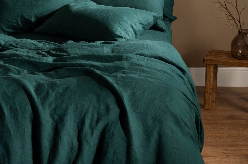 Simple autumn bedroom design with dark teal bedding, a faux fur rug, and wood flooring.