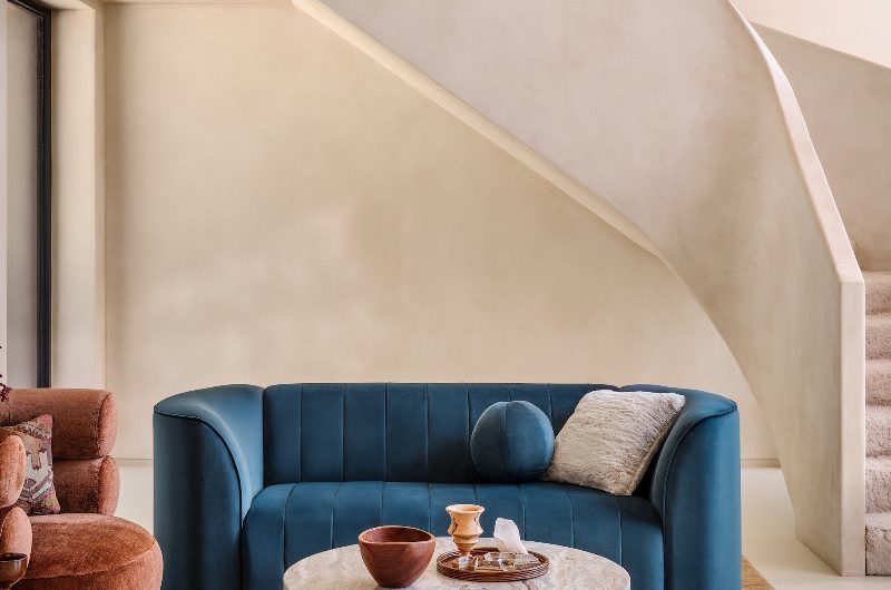 Autumn living room with a glamorous mid-century feel, colourful sofas, stone tables, and a patterned rug.