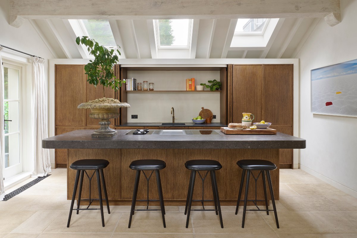 A striking island wrapped in honed dark stone, serving as a central cooking hub and casual breakfast bar. 