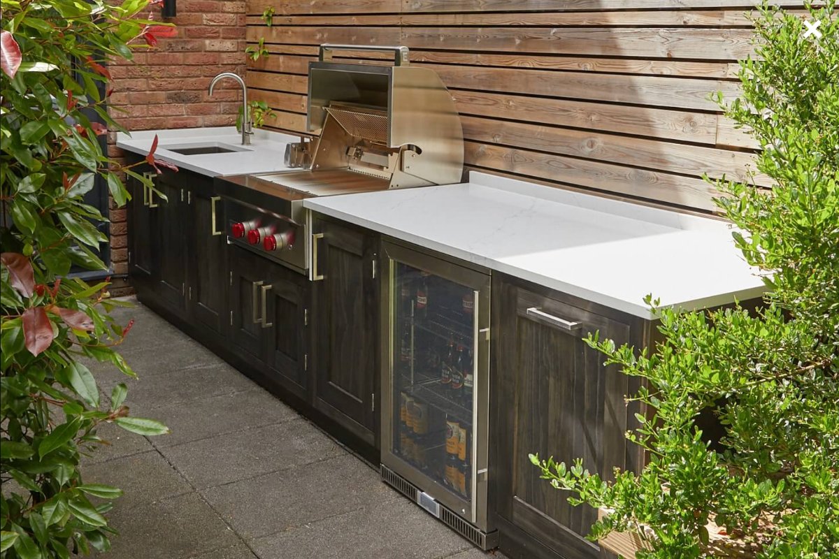 Outdoor kitchen with storage, work surface, barbecue, sink and tap, and built-in drinks fridge.