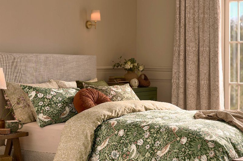 Neutral space with timeless furnishings, patterned curtains, and wall lights.
