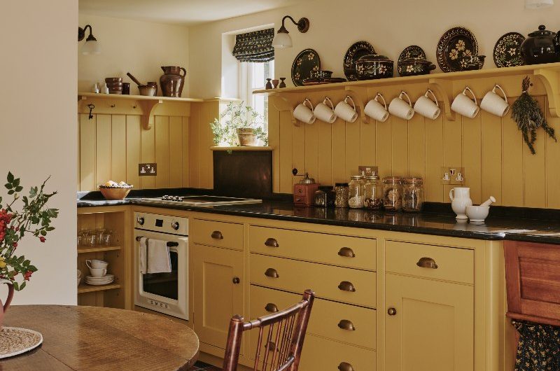 A guest yellow kitchen with checkerboard flooring, wood accents and brass hardware.