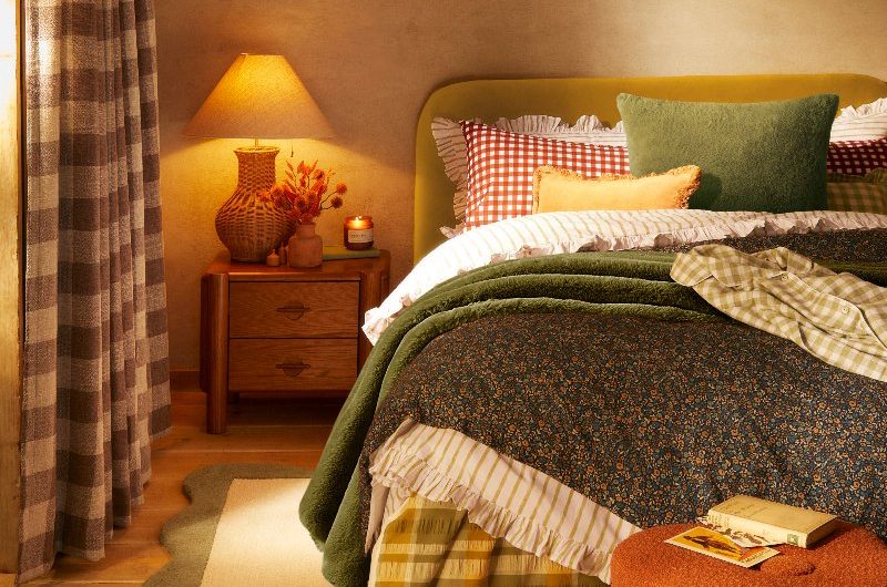 Autumn themed bedroom with a pumpkin-shaped pouffe, a scalloped rug, and a statement bed with patterned bedding.