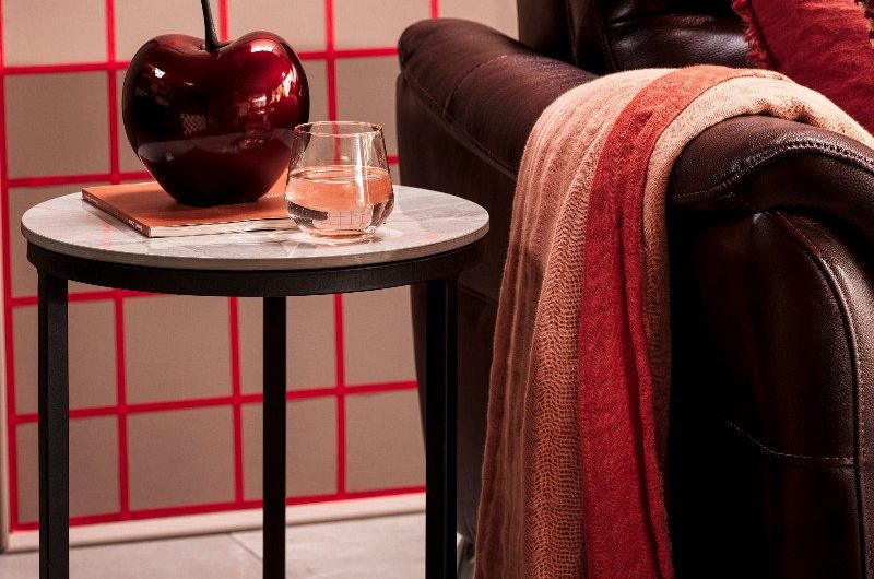 Closeup at a leather sofa with a marble and black steel frame table with an oversized cherry decoration piece.
