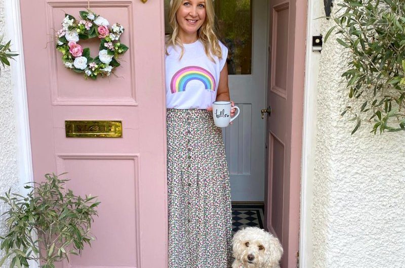 Home owner Sarah and her dog in front of her pink door.