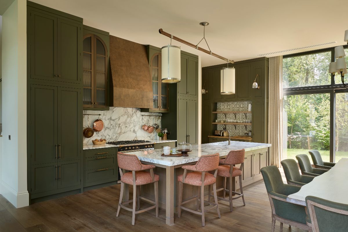 Artisan kitchen with dark green cabinetry, bronze-effect extractor canopy, and wood flooring.
