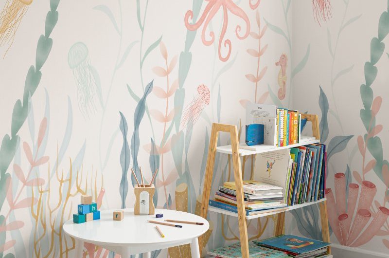Sea-inspired playroom with watercolour style mural and simple white and wood furniture.