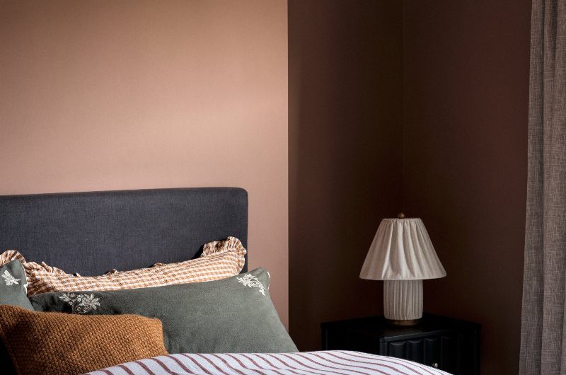 Autumn bedroom design with patterned bedding and a compact bedside table with a lamp.