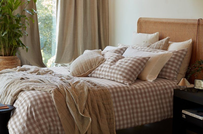 Autumn bedroom with gingham bedding in neutral tones, with a tactile rug and oversized pendant light.
