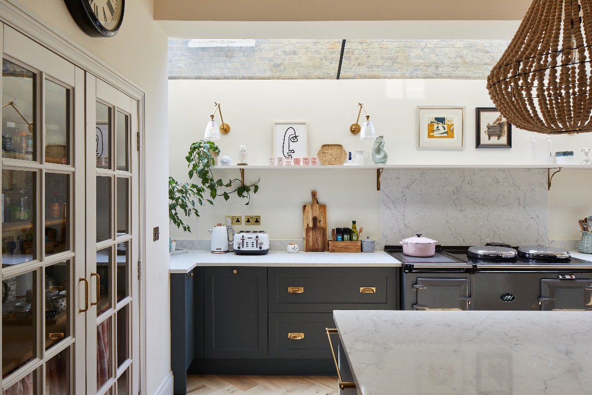 Galley kitchen painted in dark grey with veiny work surfaces, a skylight above it, a walk-in pantry and central island.