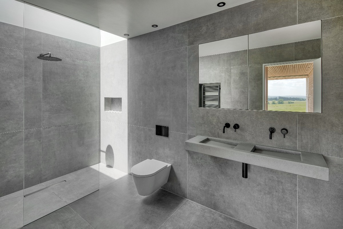 A grey bathroom design with large format tiles and concrete-effect basin.