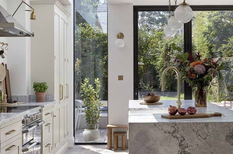 A bright kitchen design with Shaker cabinetry, a stone-clad island, and a wide expanse of glass on the roof.