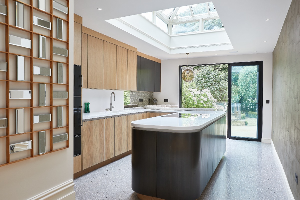 Modern kitchen design with wood furniture, a dark island clad in white surfaces and a roof lantern.