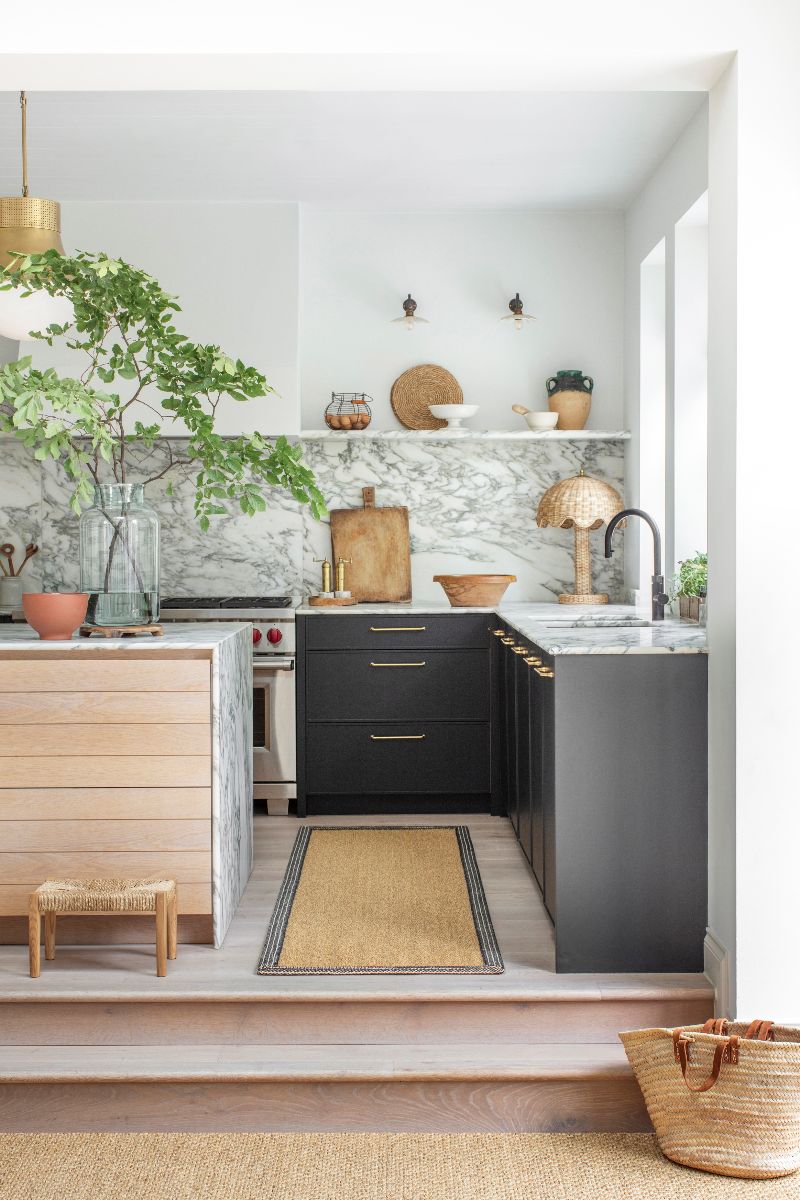 A kitchen design with dark cabinetry, marble surfaces, an island, and a recycled rug.