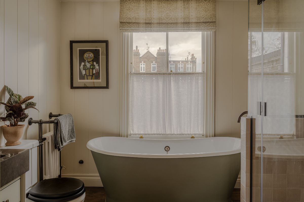 Neutral bathroom design with wall panelling, a freestanding tub, wall art, soft furnishings and a shower zone.