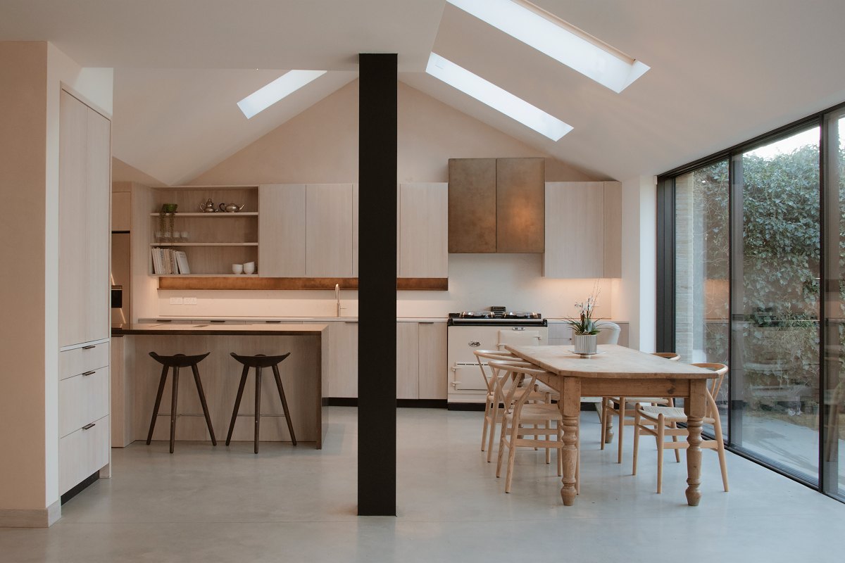 Bright kitchen design with layered lighting scheme, glazing, roof lights, and wood furniture.