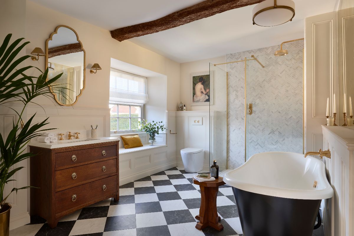 Classic scheme with checkerboard flooring, vintage vanity unit, panelling and window seat, plus a shower zone and freestanding tub area.
