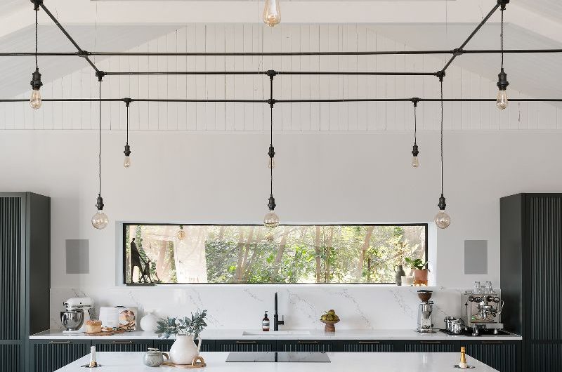 Closeup at the kitchen island with drawers, open shelves, hob and bottle coolers.
