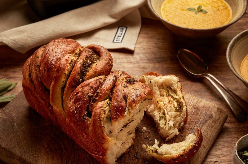 Autumn tablescape with a bread loaf, soup in rustic bowls and herbs and spices. 